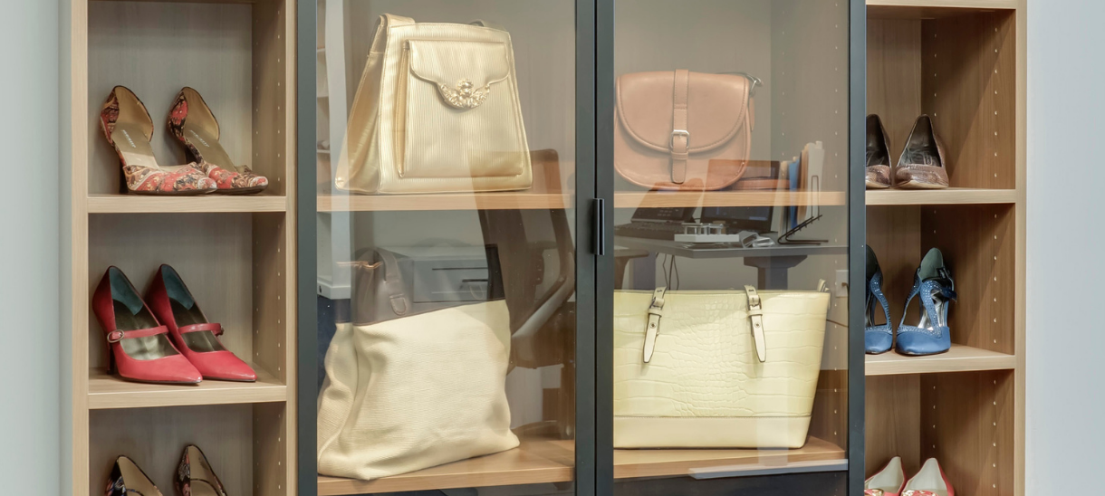 A boutique-inspired closet with aluminum frame glass doors and integrated shelving for handbags and accessories.