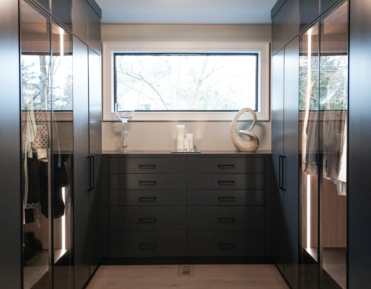 A tailored wardrobe system featuring AF012 aluminum frames in an Onyx finish and clear glass display doors.