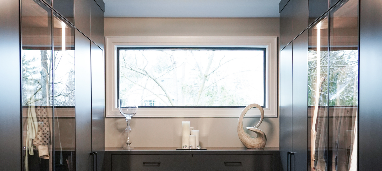A tailored wardrobe system featuring AF012 aluminum frames in an Onyx finish and clear glass display doors.