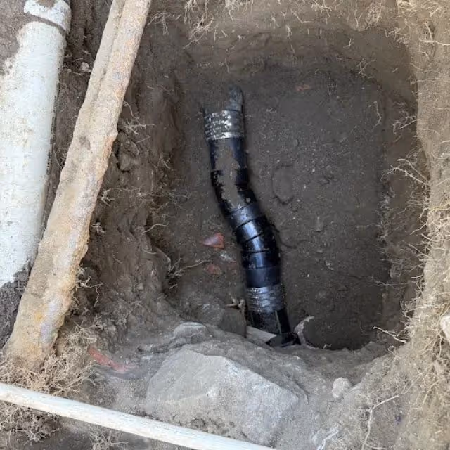 Repaired ABS sewer pipe connection in underground trench.