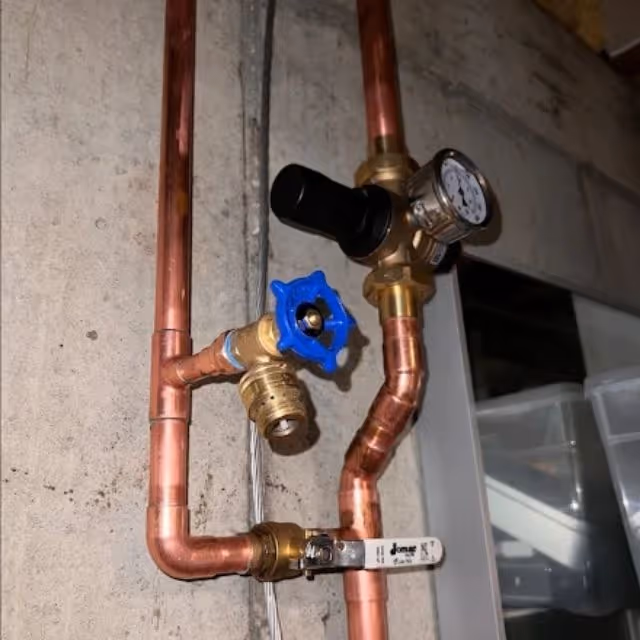 Copper plumbing with water pressure regulator and shut-off valve installation.