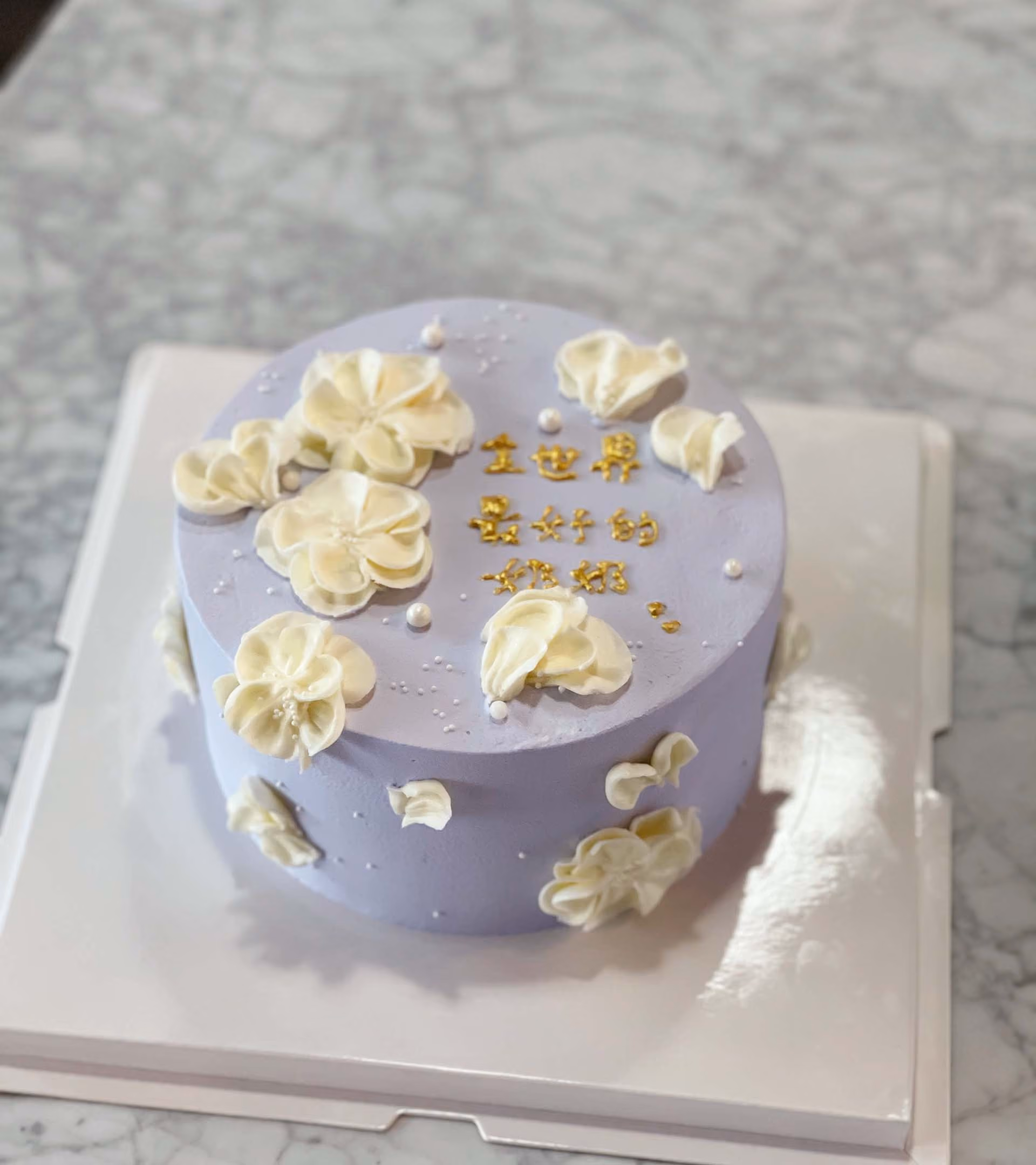 A purple cake with white frosting and flowers on top.