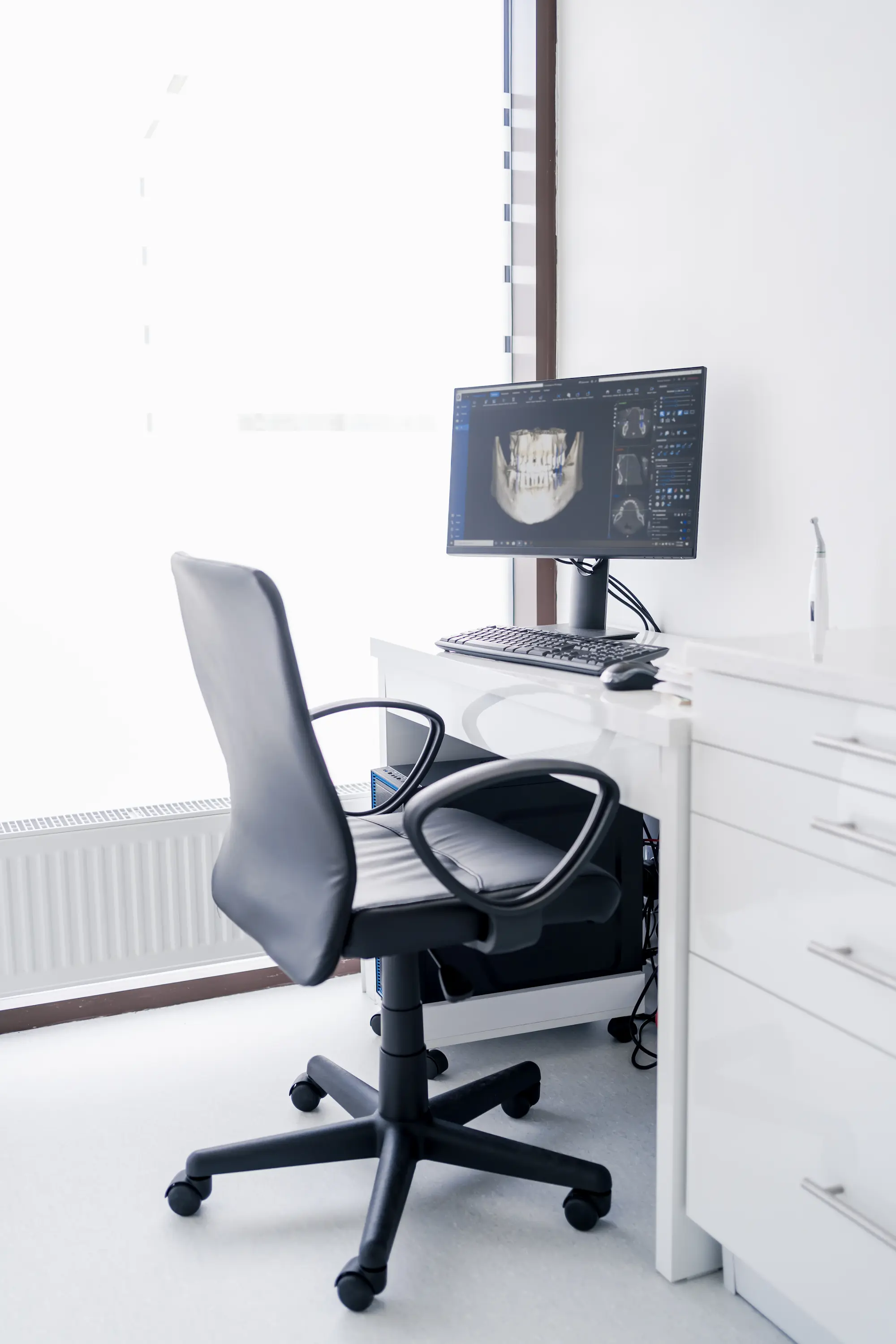 Office chair in front of a desk with a computer monitor displaying a dental X-ray scan.