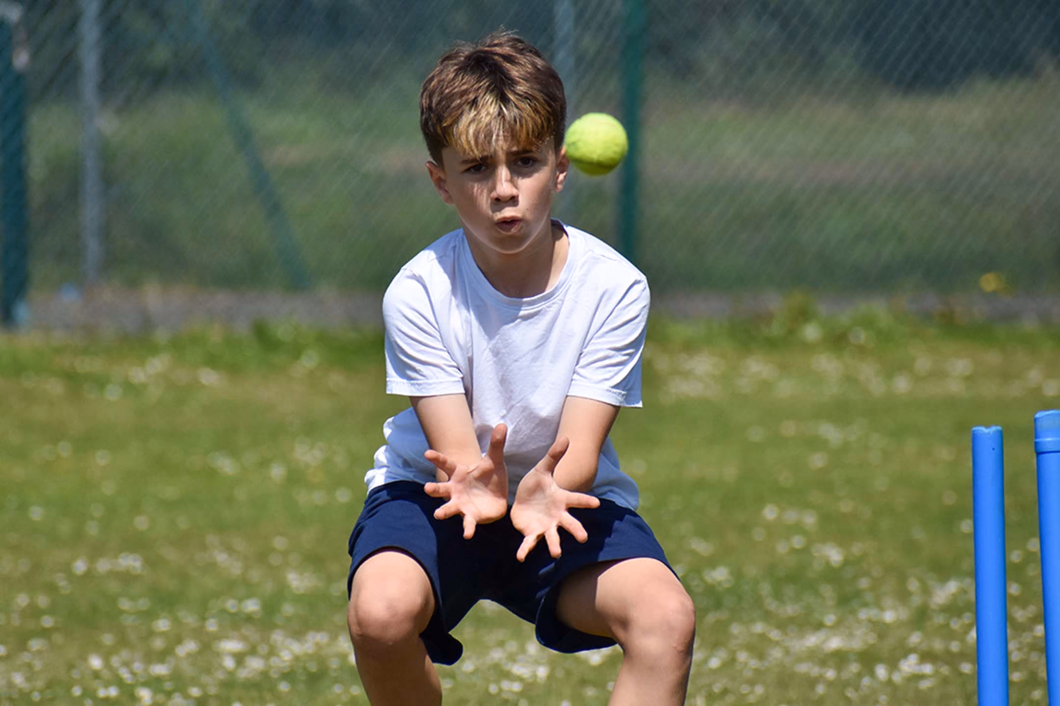 Pupil catching a ball during an outdoor cricket lesson.