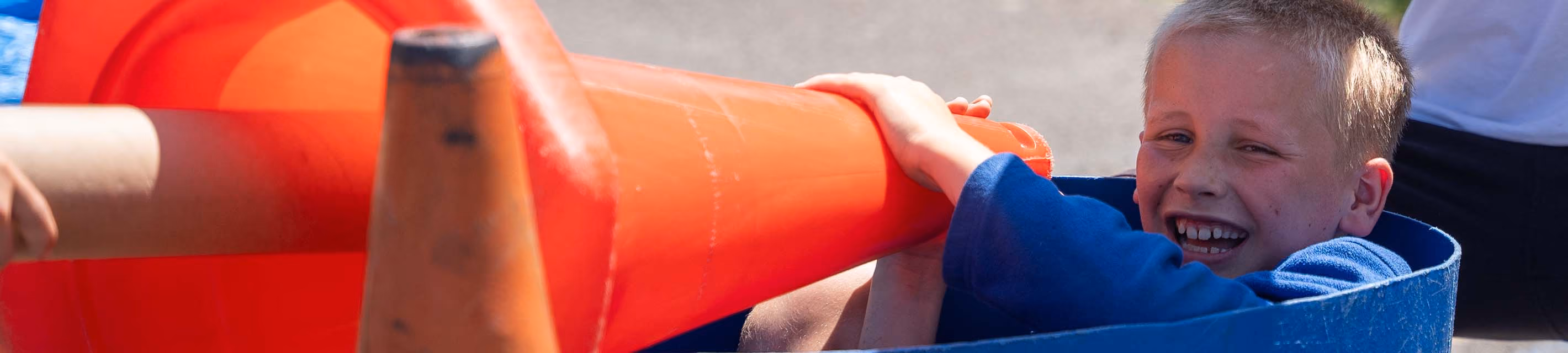 Pupil laughing while playing with traffic cones during outdoor play.