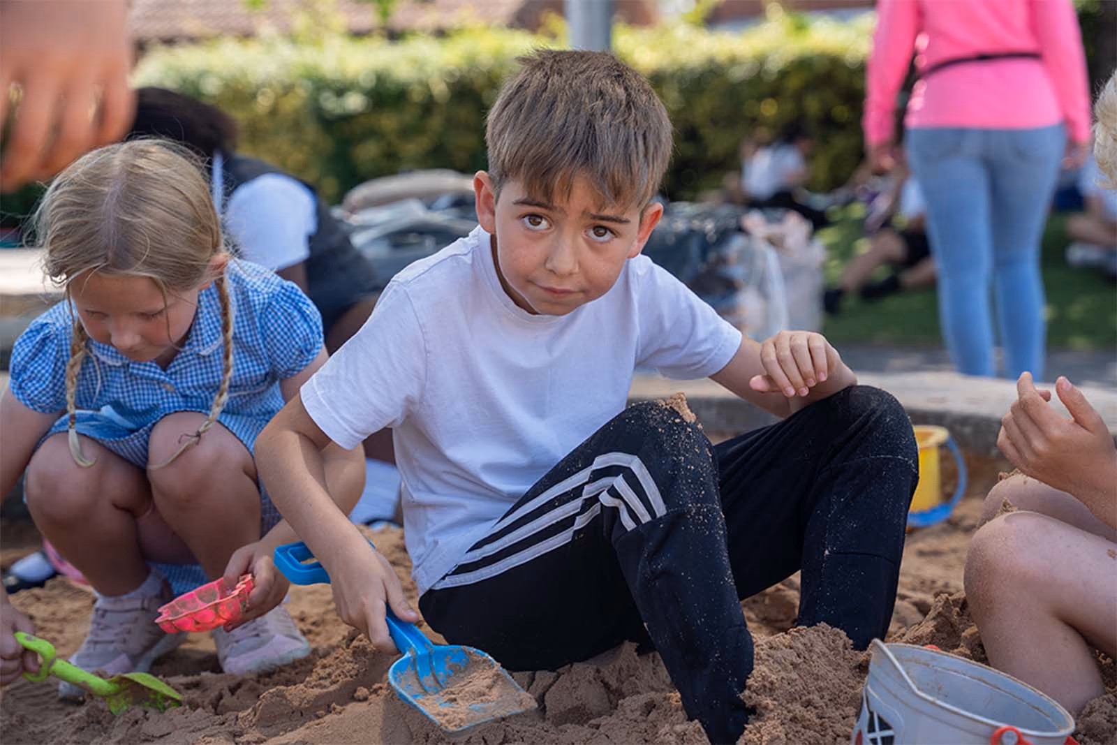 Pupils playing with sand and buckets in an outdoor sandpit.