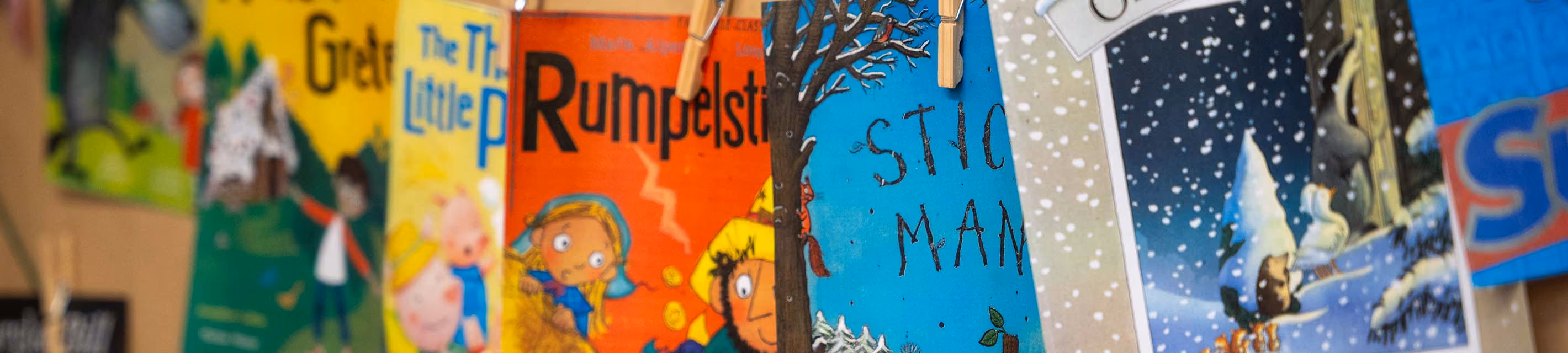 Row of favourite storybook covers, including 'Stick Man' and 'Rumpelstiltskin', pegged on a line.