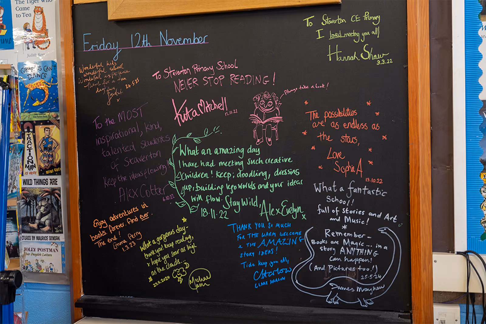 Blackboard covered in colourful messages and signatures from visiting authors at Staverton's Story Festival.