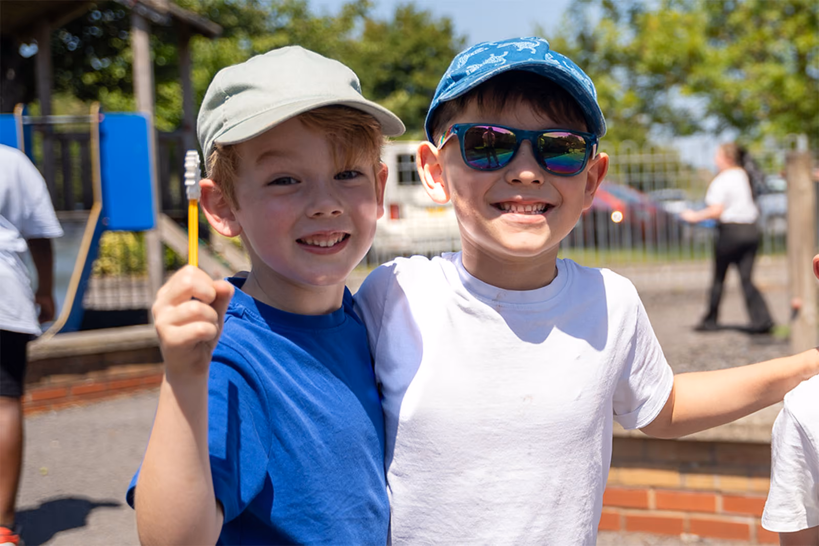 Two smiling pupils with arms around each other in the school playground.