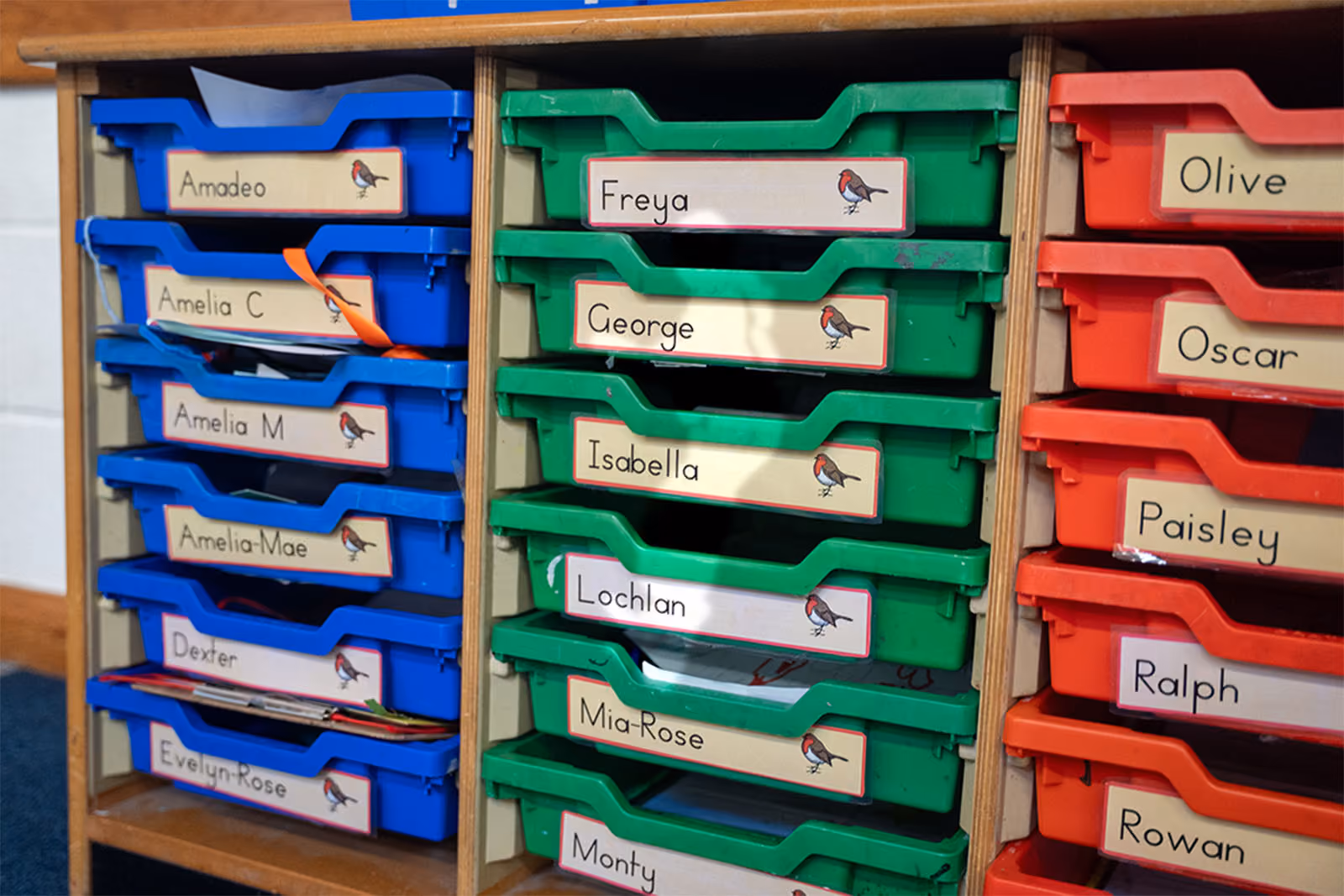 Coloured storage trays labelled with individual pupils' names.