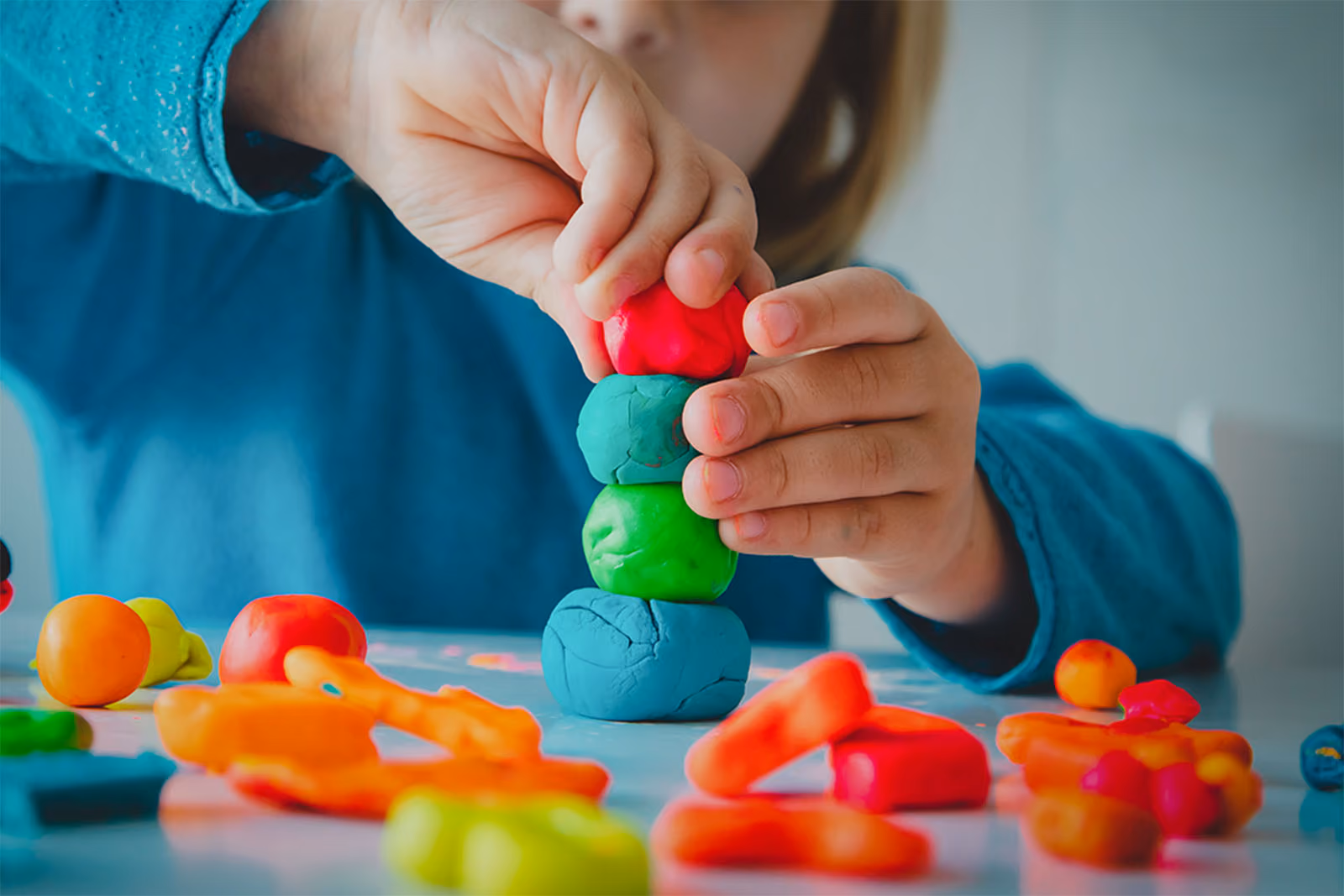 Close-up of a child stacking colourful balls of modelling dough.
