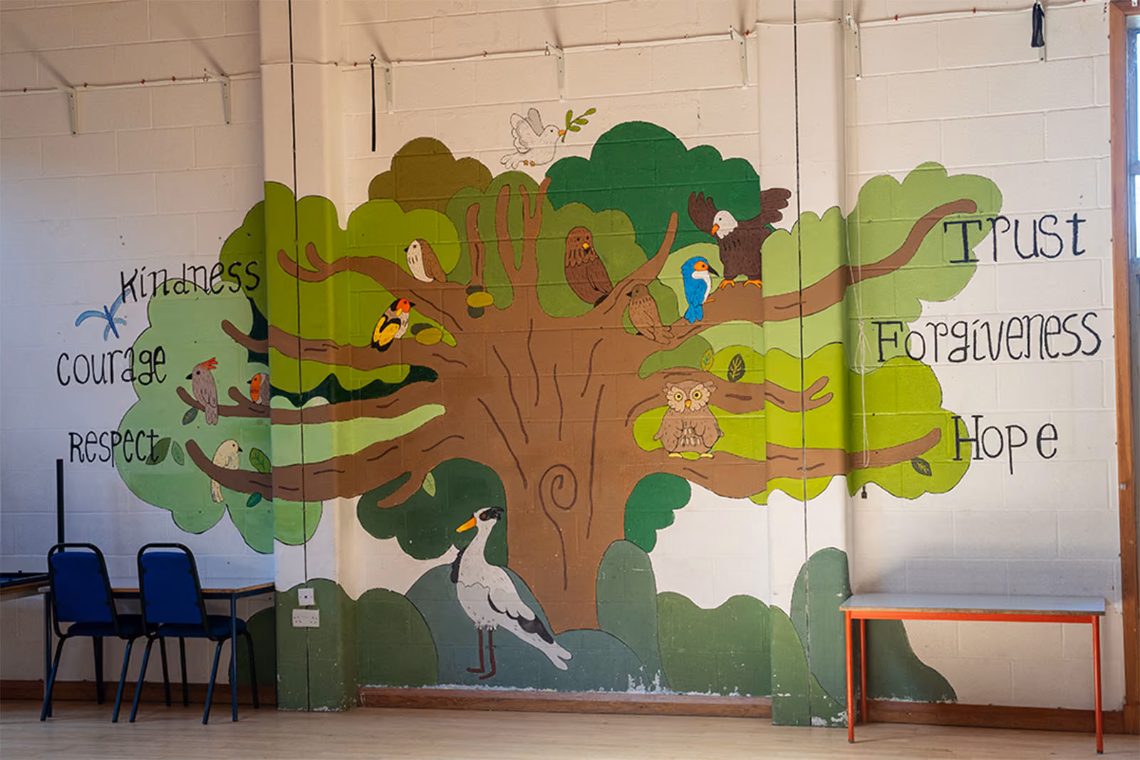 Wall mural of a tree with birds, listing the school's core values: Kindness, Courage, Respect, Trust, Forgiveness, Hope.
