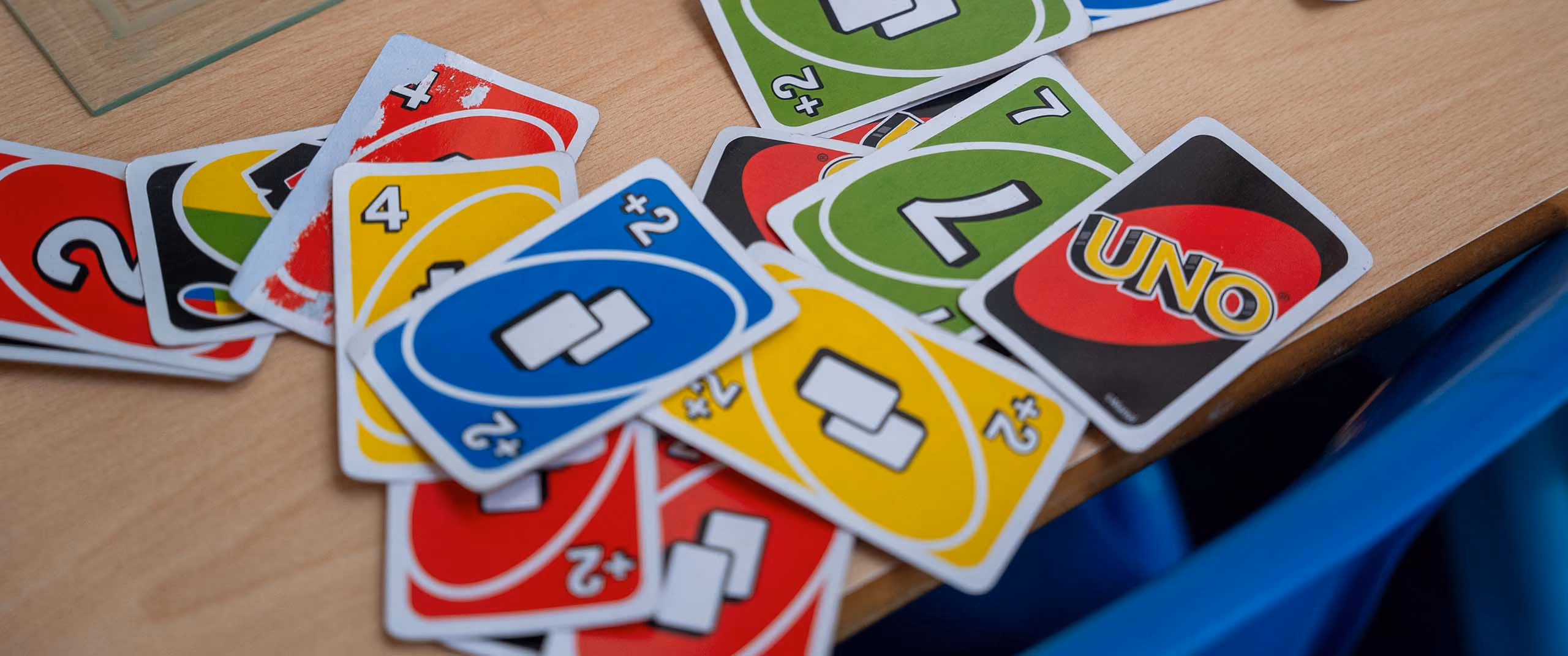 A pile of colourful UNO cards scattered on a wooden table with part of a chessboard visible.