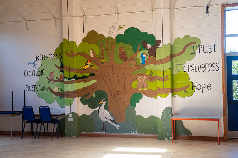 Wall mural of a tree with birds, listing the school's core values: Kindness, Courage, Respect, Trust, Forgiveness, Hope.
