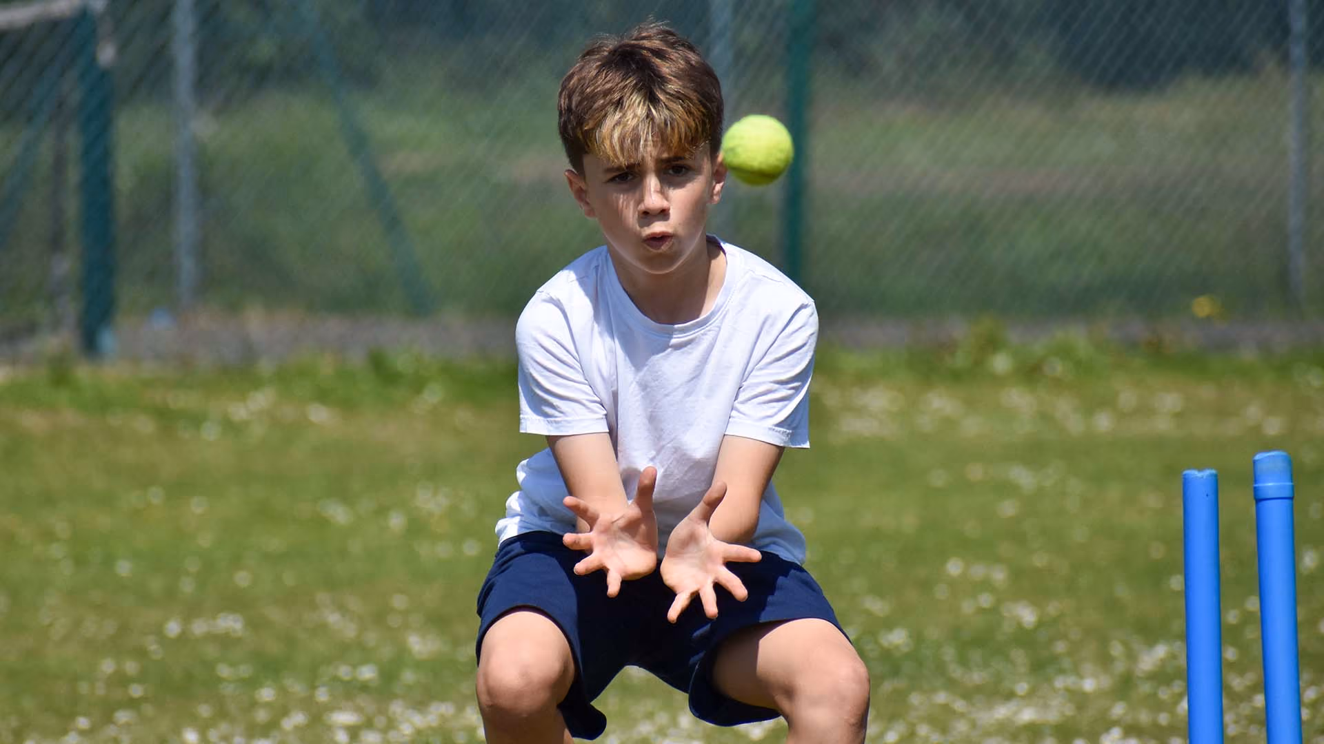 Pupil catching a ball during an outdoor cricket lesson.