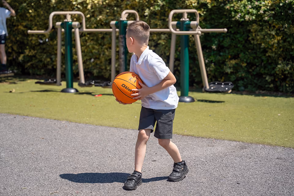 Pupil holding a basketball on the school playground.