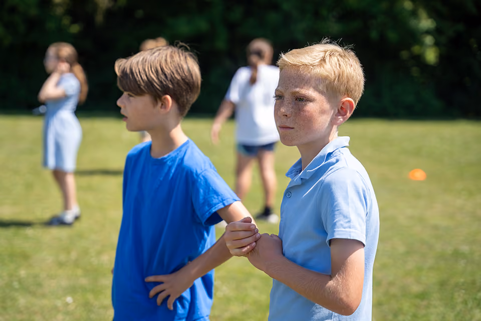 Two pupils standing together on the school field during a PE session.