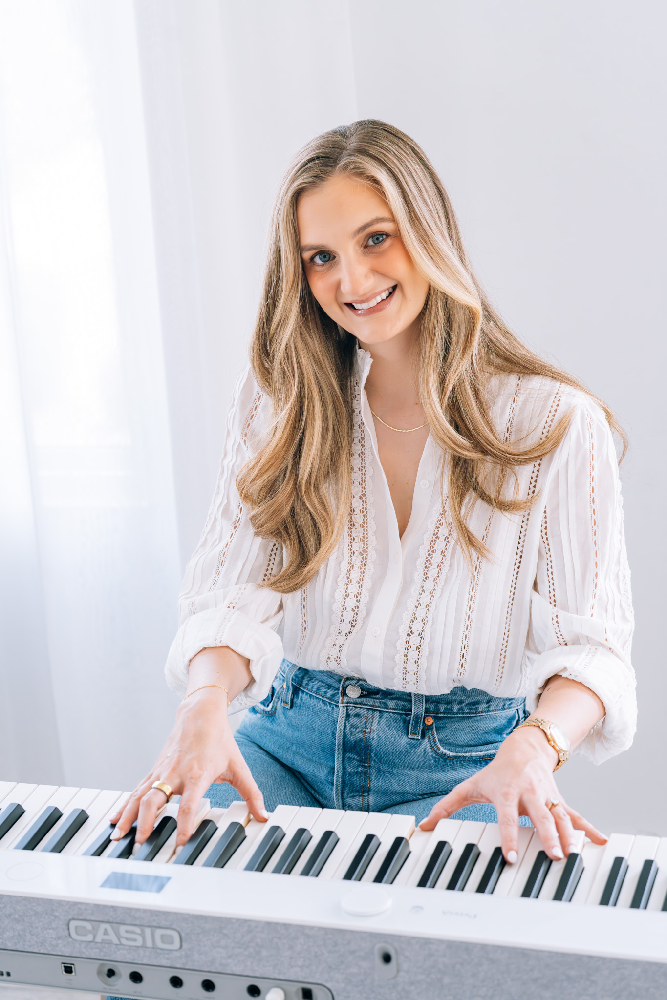 Kaitlyn smiling at a white keyboard