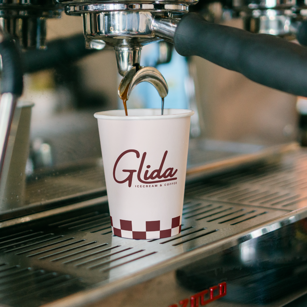 Mockup of espresso being poured into a disposable cup with Glida's logo on it.