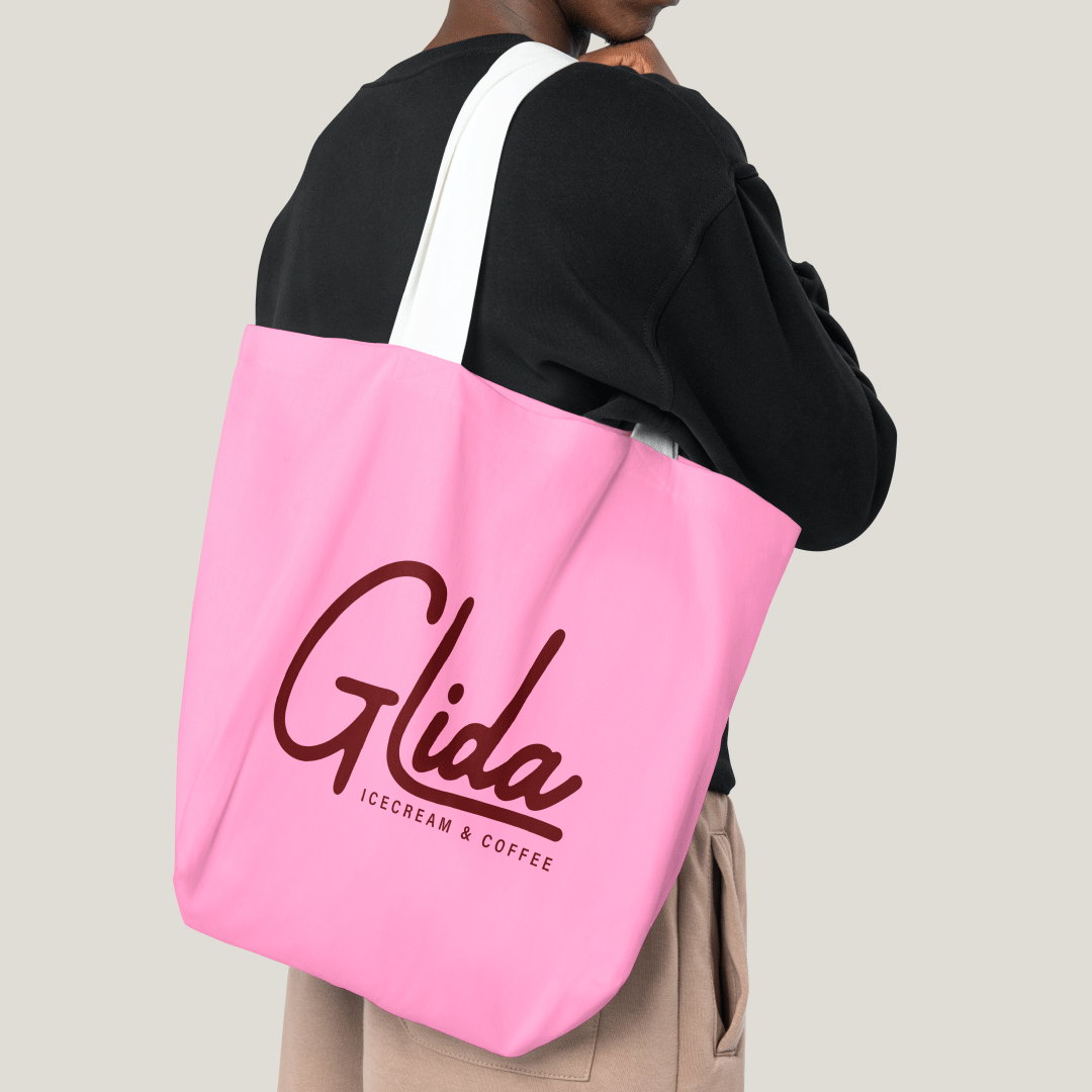 Mockup of a man with pink totebag with the Glida's logo on it.