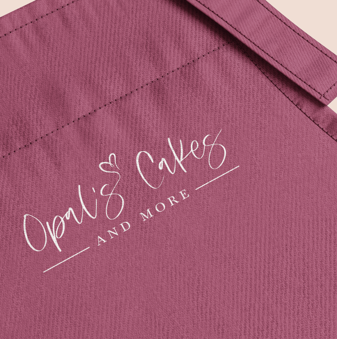 Apron in the brand's primary color with the Opal's Cakes and More logo on it.