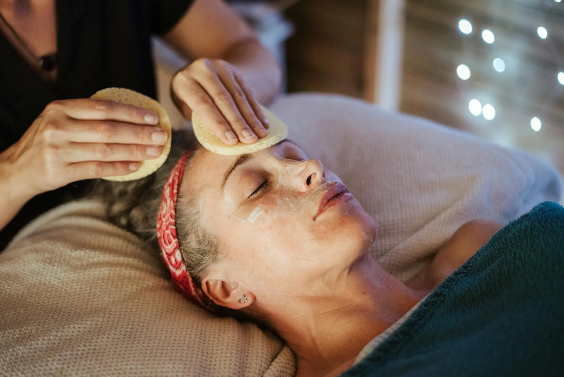 A woman laying on a bed with a hair dryer on her head.