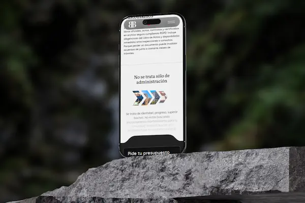 iPhone mostrando una web apoyado verticalmente en una plataforma rocosa con un fondo vegetal desenfocado
