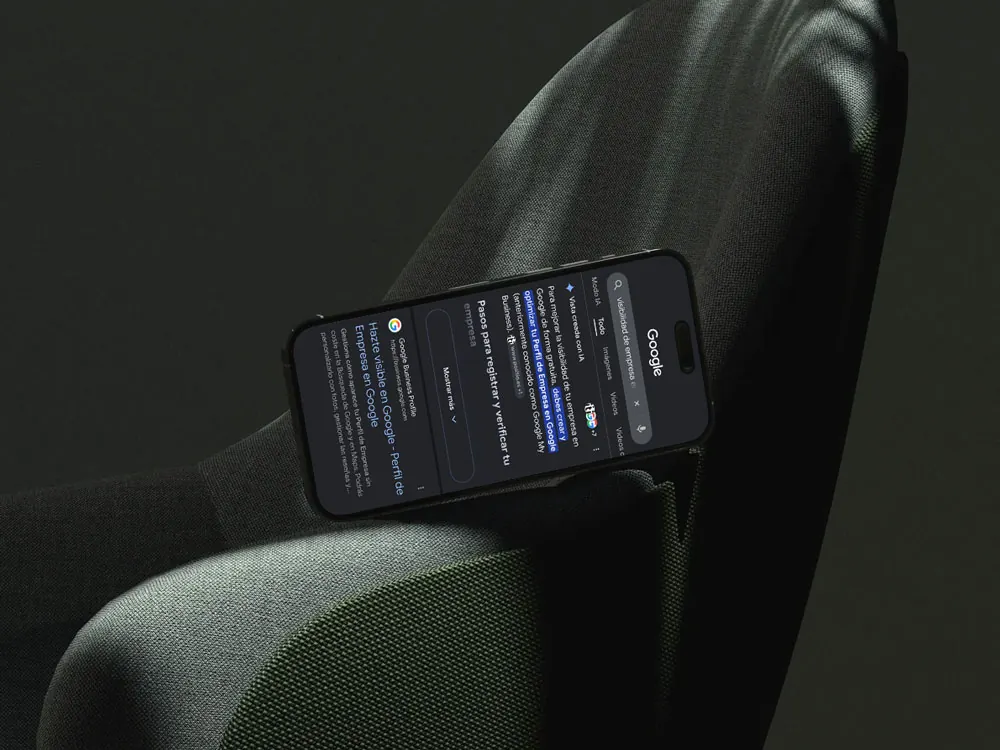 iPhone tumbado en el posabrazos de un sillón mostrando una búsqueda de Google