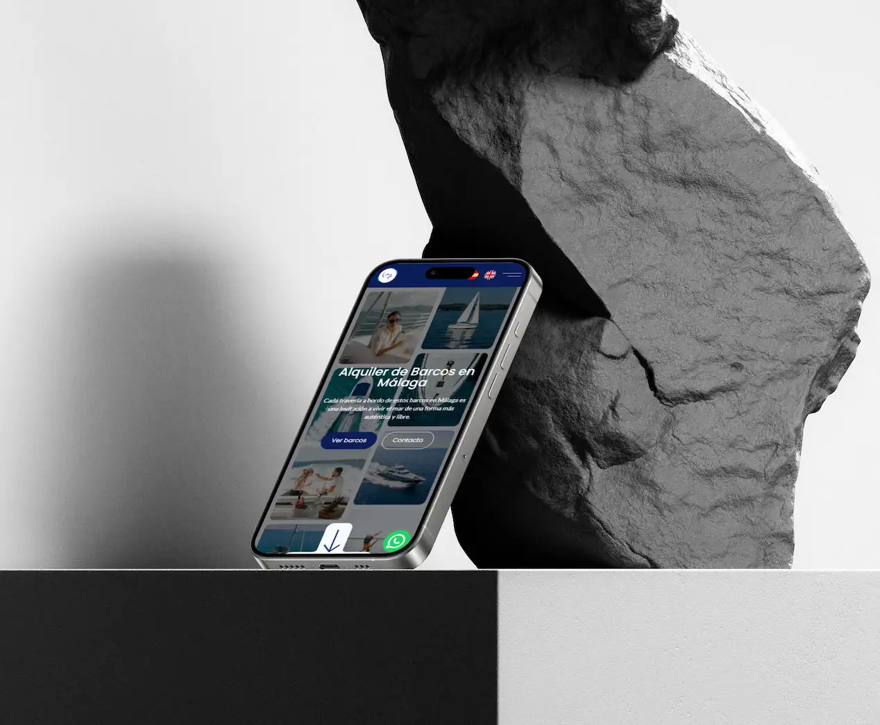 iPhone 17 apoyado en una roca mostrando la web de Oceanalquiler