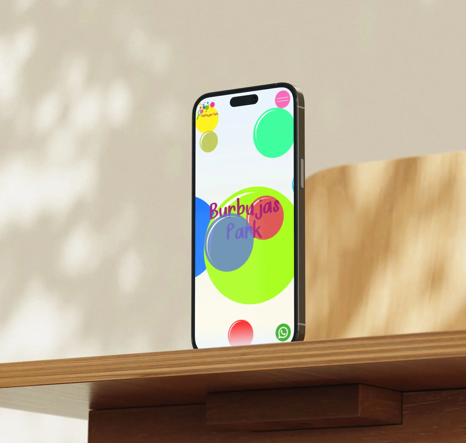 iPhone apoyado sobre una repisa de madera mostrando la web de Burbujas Park