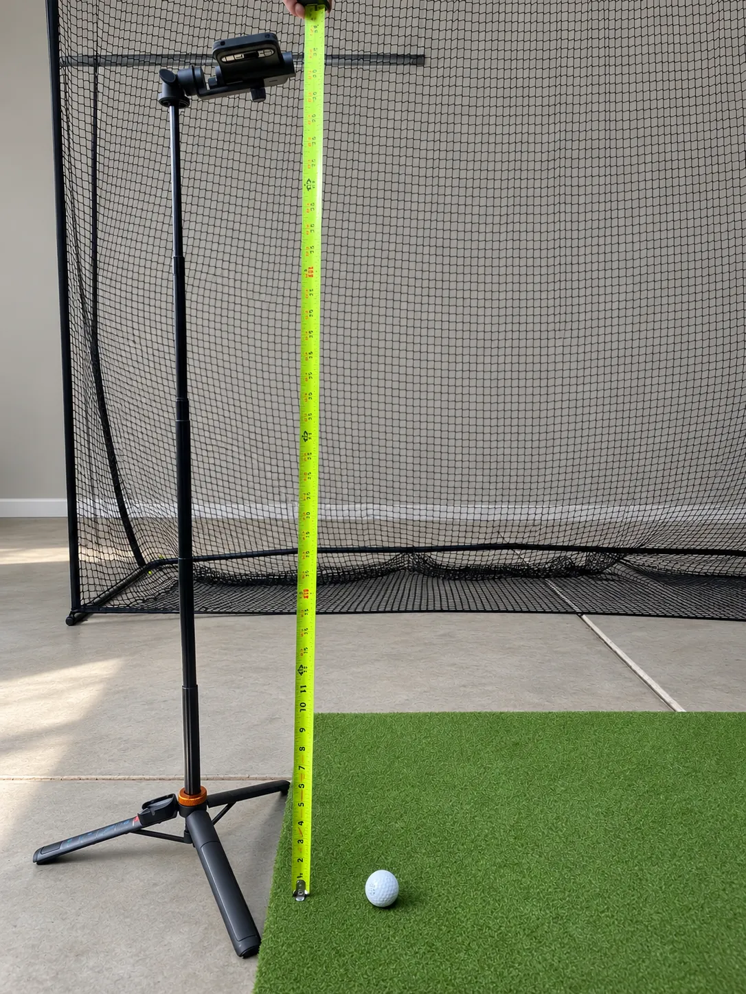 A tape measure held vertically beside a mounted phone to measure the height from the ground to the camera lens.