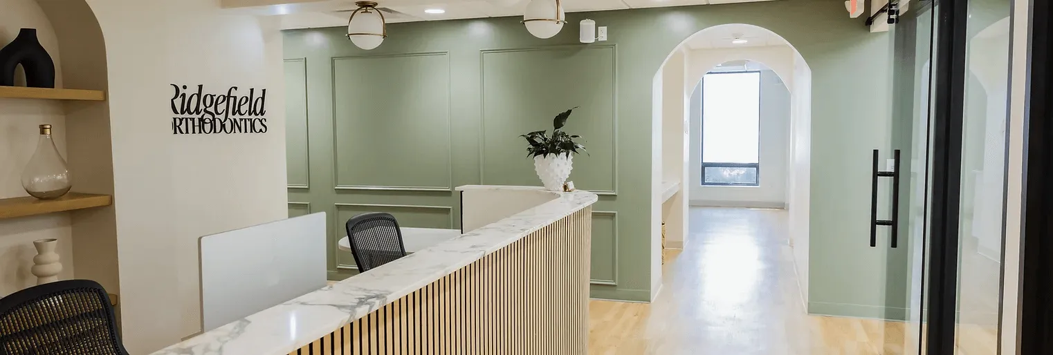 Front desk of the Ridgefield Orthodontics office in Ridgefield, CT with sage green walls