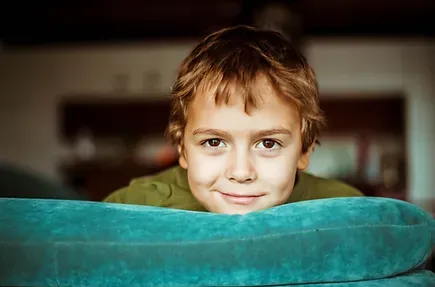 Young boy smiling over the back of a couch