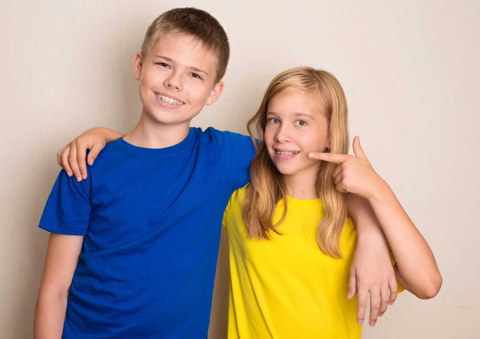 Girl with braces pointing at her smile next to a boy in a blue shirt.