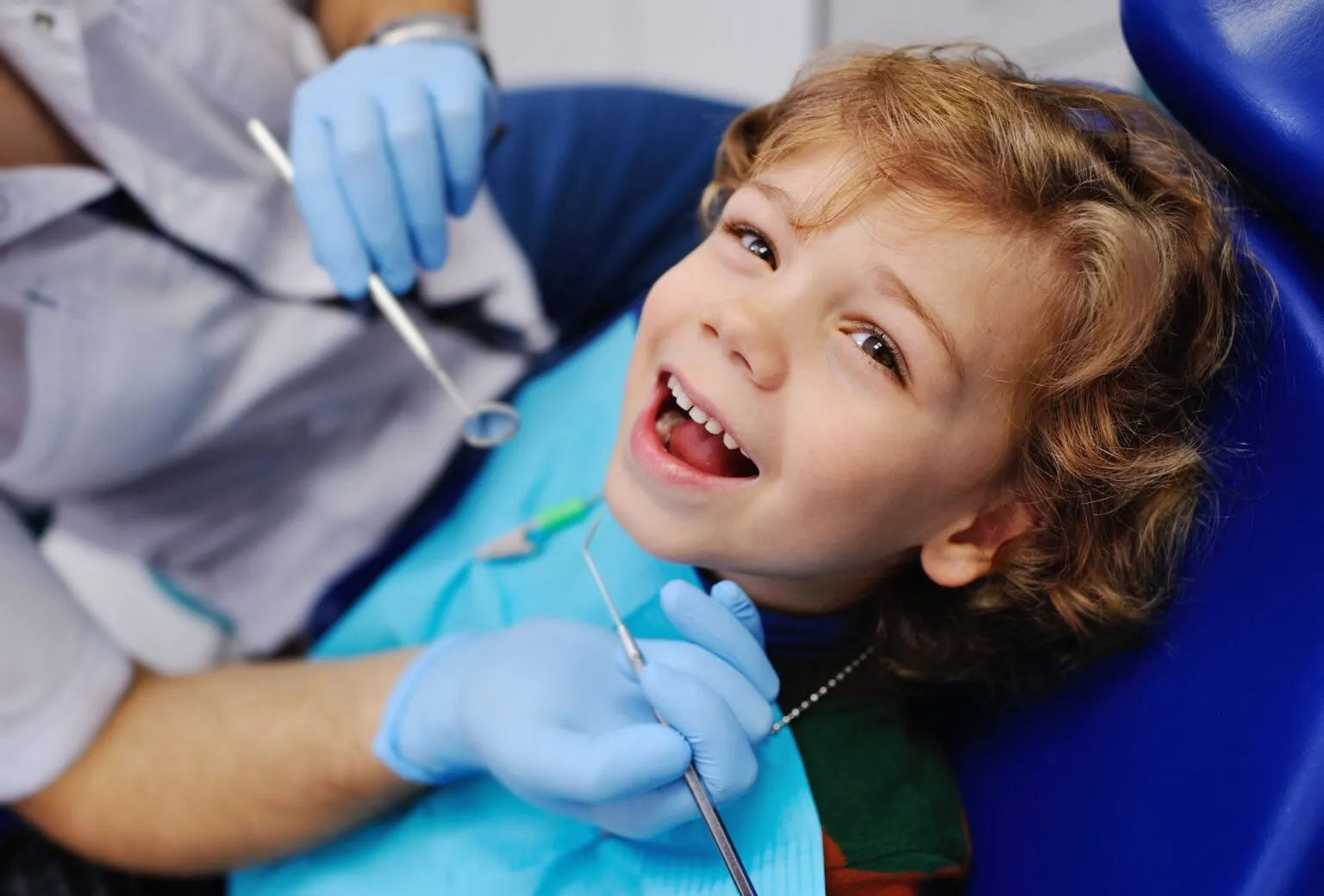 Young boy smiling in a dental chair during an orthodontic exam.