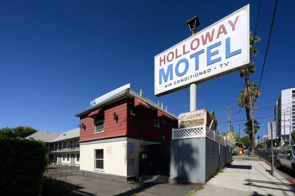 Vintage motel sign with red building facade and blue sky