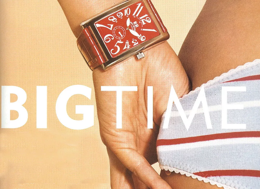 Red rectangular wristwatch on a wrist against a striped fabric background