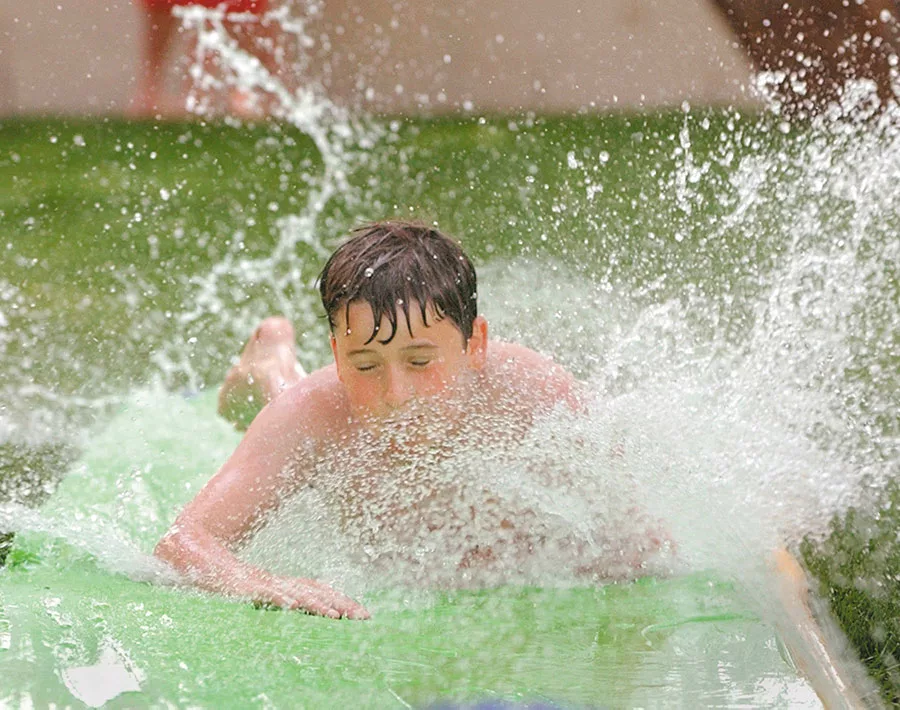 Child joyfully sliding on a water slip 'n slide