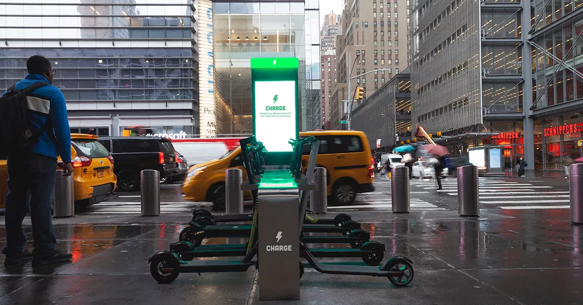 Electric scooters parked at charging station on rainy city street