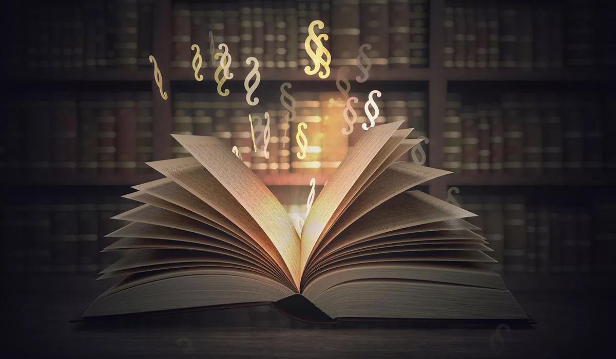 Open book with glowing pages and floating legal symbols in a dimly lit library.