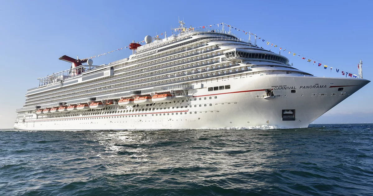 Large cruise ship Carnival Panorama sailing on open sea under a clear blue sky.