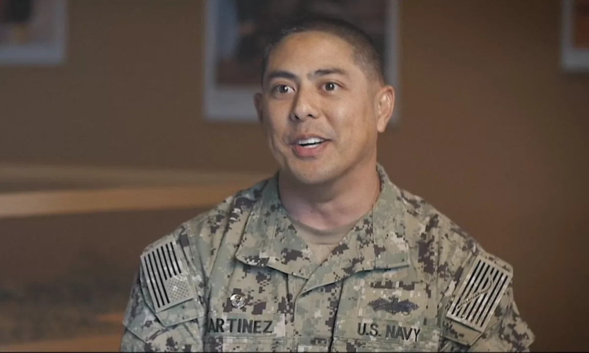 U.S. Navy officer in camouflage uniform smiling indoors