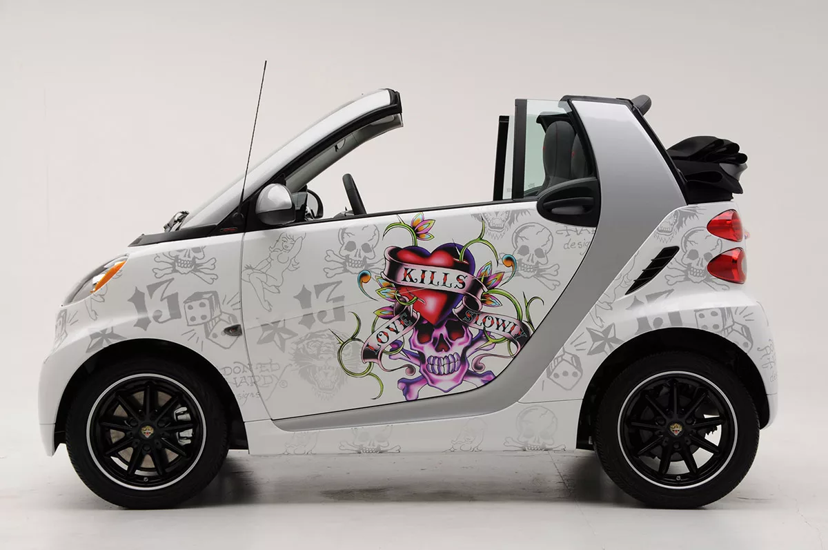 White smart car with edgy tattoo art featuring a red heart and skull design