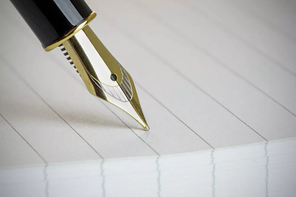 Fountain pen nib writing on lined notebook page