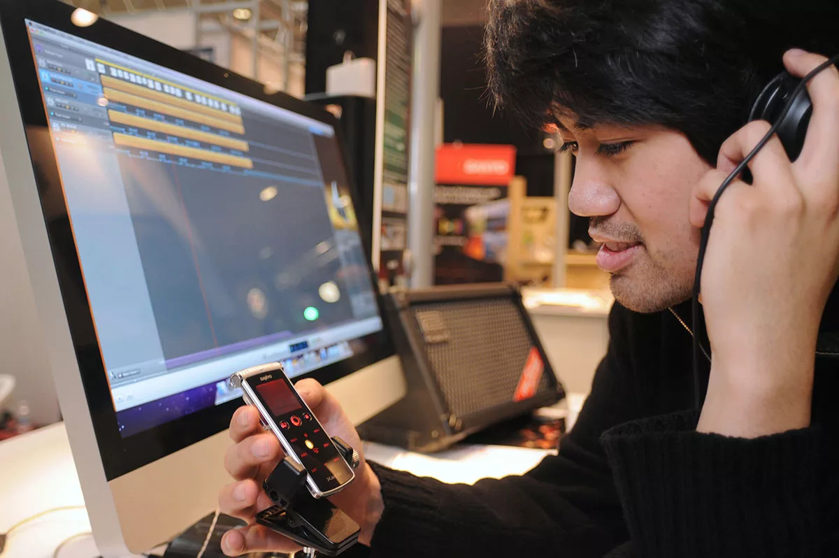 Person editing audio on a computer while using a digital audio recorder in a recording studio.