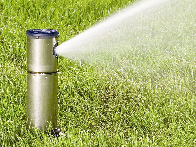 Sprinkler system watering lush green lawn on a sunny day