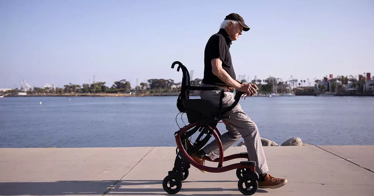 Senior man using a walker along a waterfront path