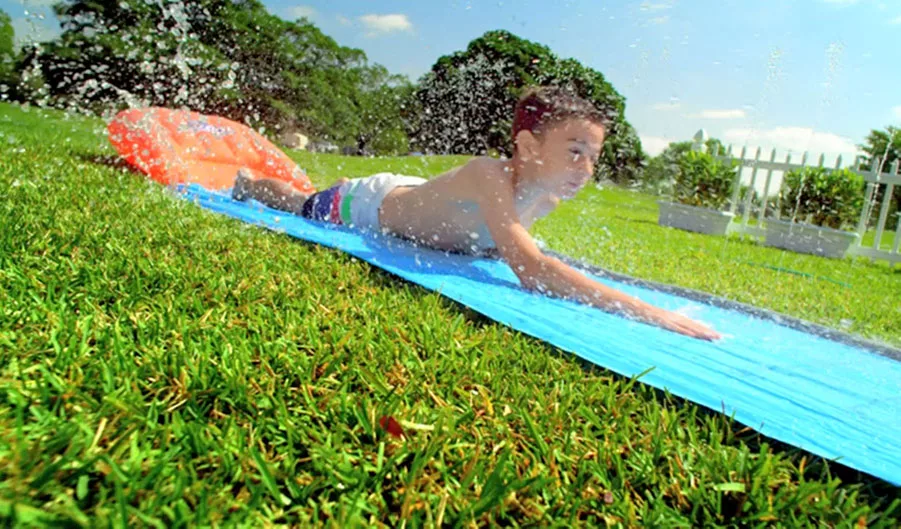 Child sliding down a water slip and slide on a sunny day