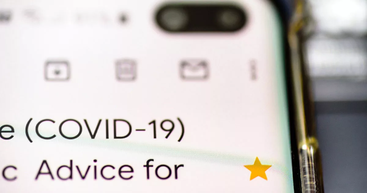 Close-up of smartphone screen displaying COVID-19 text with app icons and a yellow star.