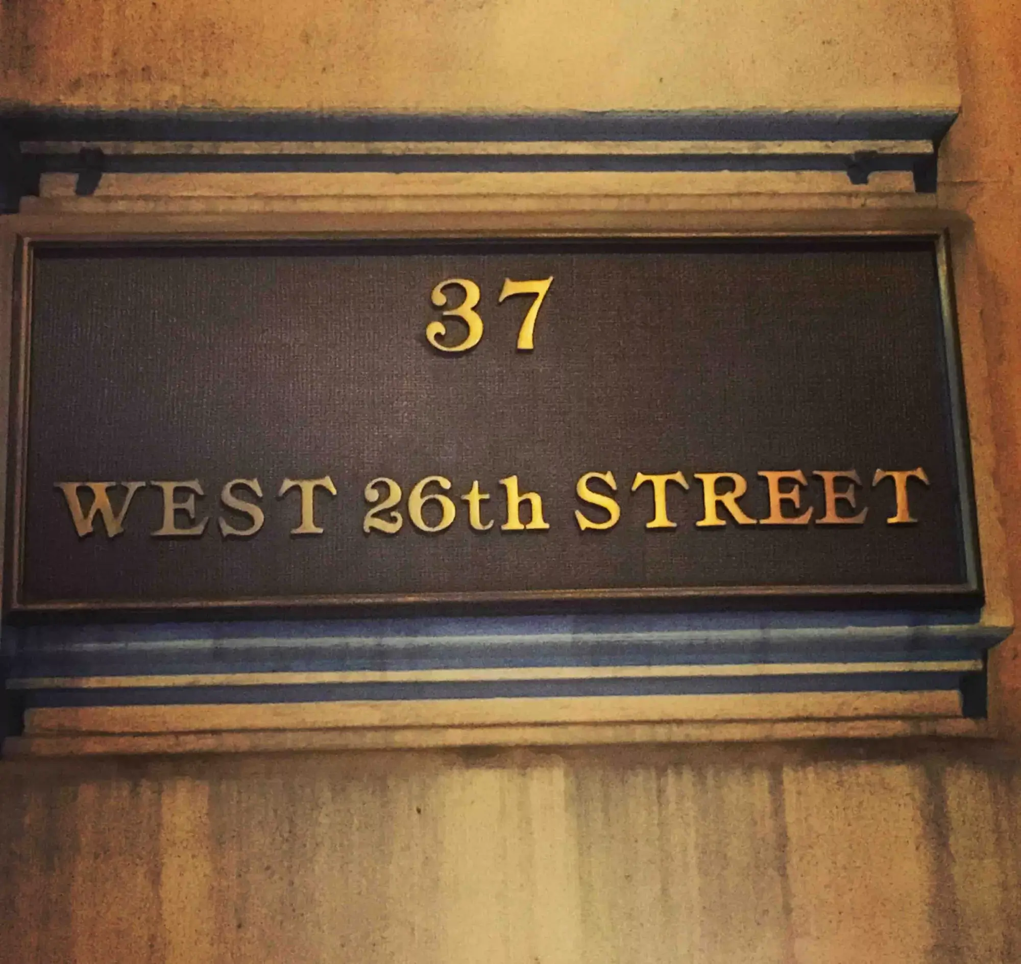 Building address plaque showing "37 West 26th Street" with gold lettering on a textured background.